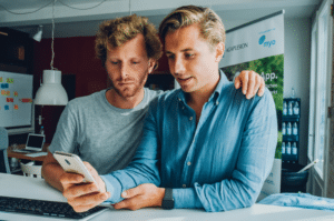Felix & Jasper, die Gründer der Myo App, sehen sich die App auf dem Smartphone an