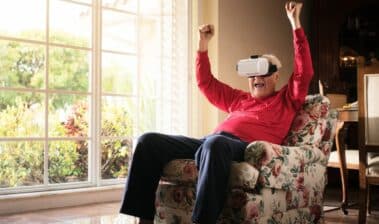 Alte Frau im Sessel hat Spaß mit ihrer VR-Brille
