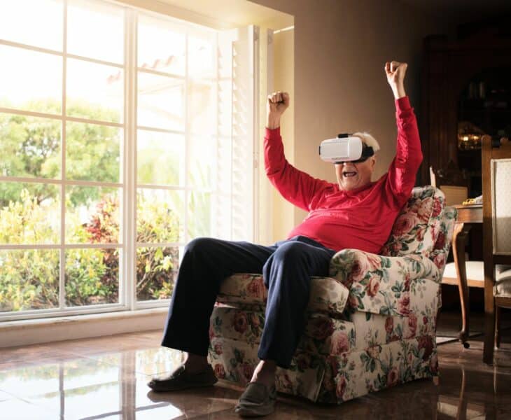 Alte Frau im Sessel hat Spaß mit ihrer VR-Brille