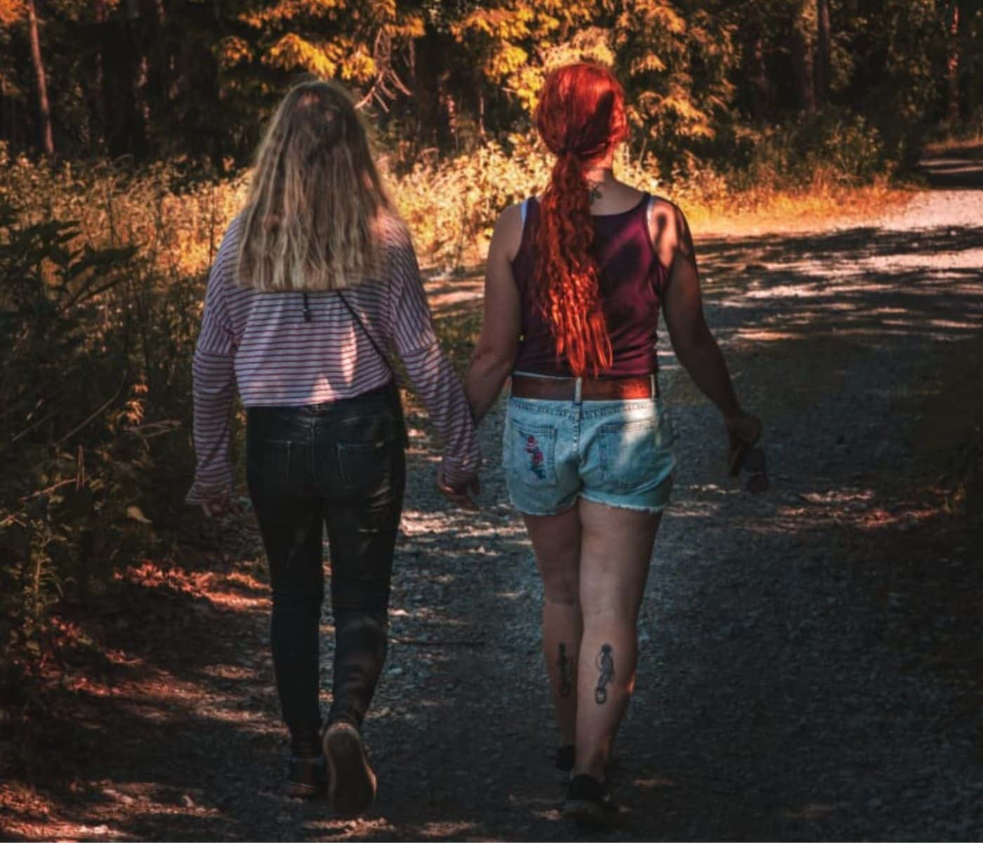 Symbolbild: Alleinerziehende Pflegekraft: Mutter und Tochter gehen händchenhaltend im Wald spazieren und werden von hinten fotografiert